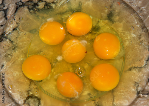Seven raw eggs in a clear bowl
