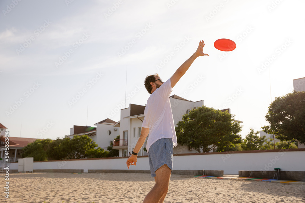 Man catching Frisbee on the beach. Game of Frisbee. Beach activities. Time to relax. Summer entertainment