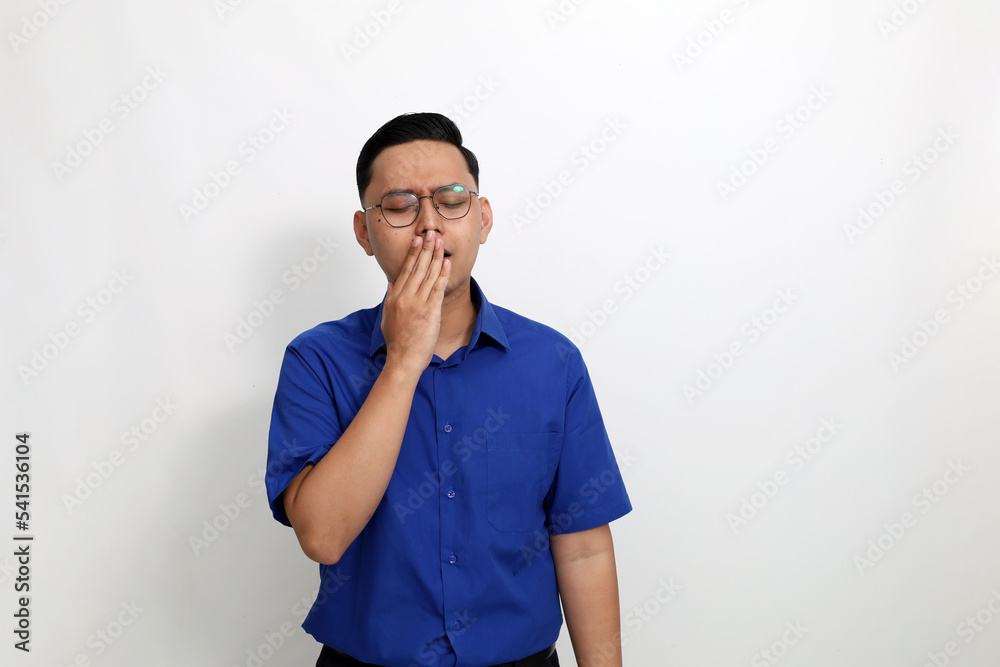 Young asian man standing while yawing. He feels tired. Isolated on white background with copyspace Young asian man standing while yawing. He feels tired. Isolated on white background with copyspace