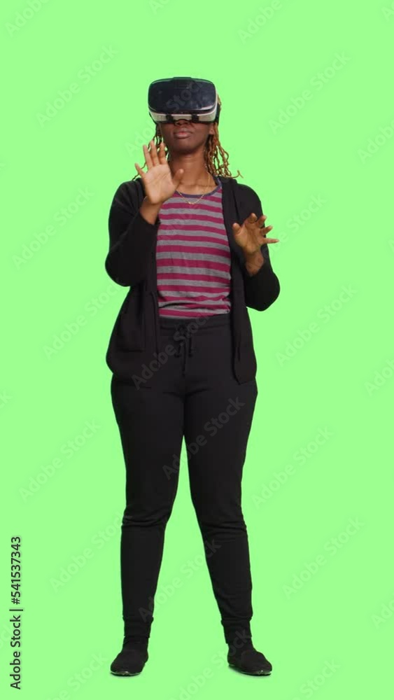 Vertical video: Young adult using vr glasses with full body over green screen backdrop, having fun with virtual reality 3d headset. Enjoying technology and artificial intelligence on greenscreen Vertical video: Young adult using vr glasses with full body over green screen backdrop, having fun with virtual reality 3d headset. Enjoying technology and artificial intelligence on greenscreen