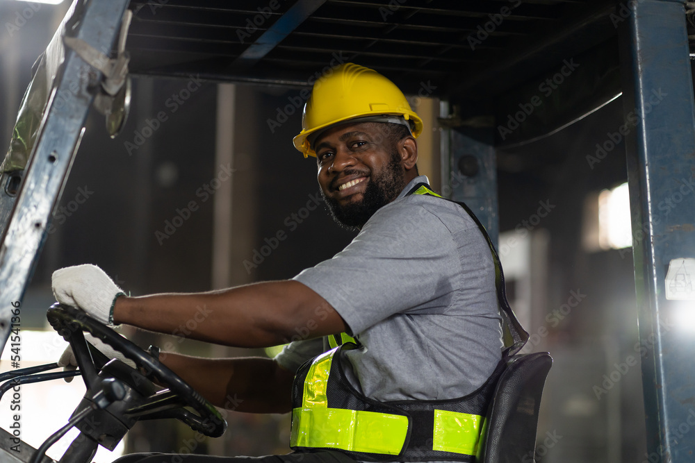 Happy African American male engineer driving and operating on forklift ...