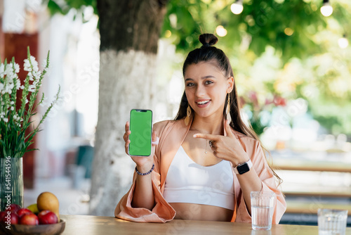 Woman hold smartphone and point at phone.
