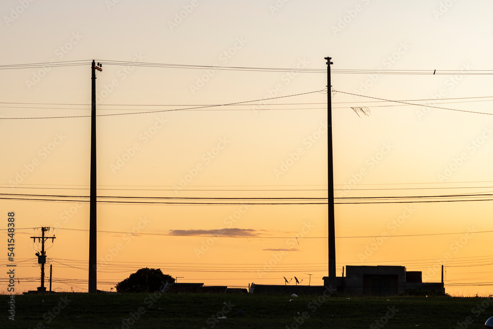 Silhouette of streetlights, houses and cars, during the sunset in the Brazilian city.
