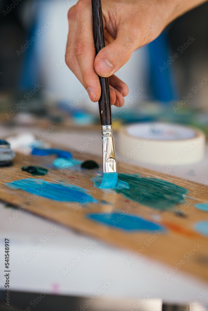 Obraz premium Artist mixes paints with a brush on a palette