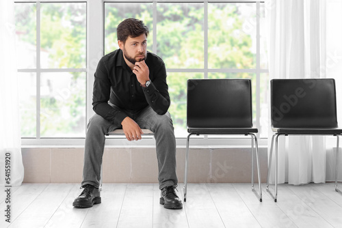 Fired young man sitting in office