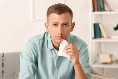 Young man with nosebleed an...