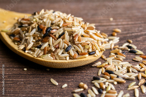 Wooden spoon on a textured background with red brown rice seven grains containing black rice, oats, wheat, barley and amaranth. Nutritious and versatile and a natural source of fiber and magnesium. photo
