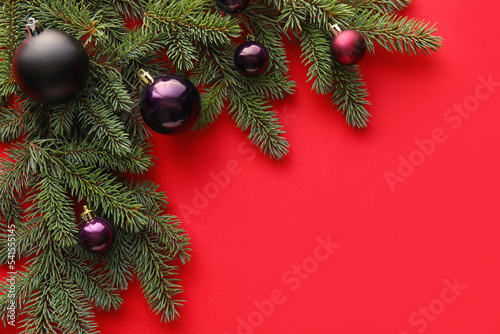 Fir branches with Christmas decorations on red background