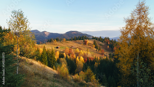 . Wooden cabin circled by colorful yellow and red autumn trees.