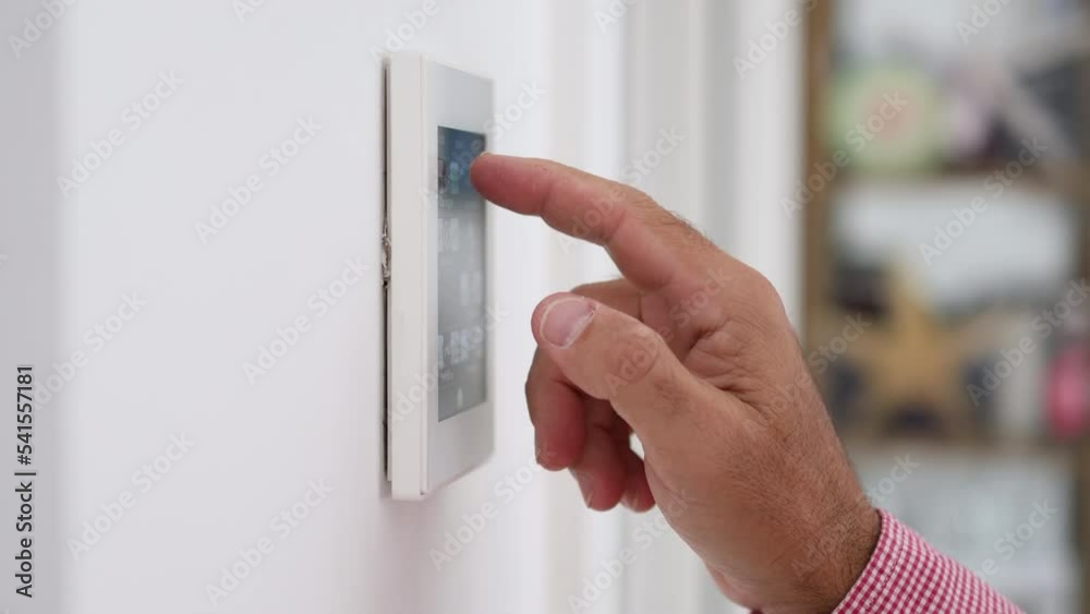Man's hand adjusting the temperature of the house on a home automation screen.