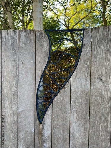 oak fence with a beautiful forged ornament. The tree: Himalayan birch photo