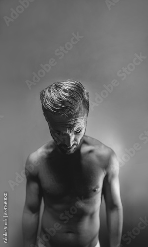 Dark creative artistic portrait of a mature naked man in black and white with copyspace. Mental health, psychology disorder, sadness or depression concept.