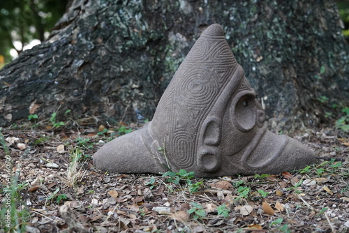 Taino Antique Stone Cemi Idol Figure sitting on the ground on top of grass. Taino Indian Mythology. photo