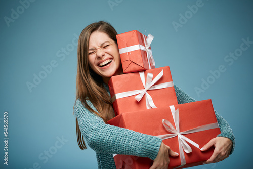 Excited happy woman holding stacj of red gift boxes. Advertising female studio portrait.