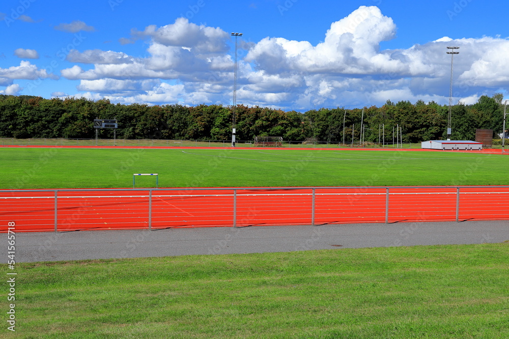 Obraz premium Part of a Stadium or sports arena. Red running tracks next to a green lawn. Sunny day outside. Bålsta, Stockholm, Sweden, Scandinavia, Europe.