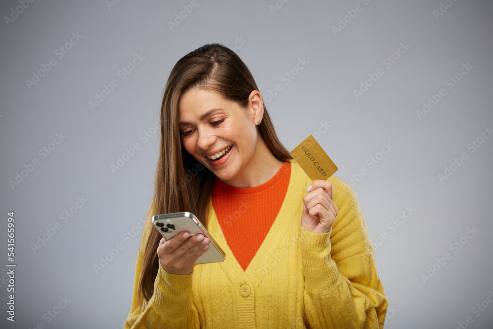 Woman in yellow using credit card and smartphone for shopping. Isolated female advertising portrait. Woman in yellow using credit card and smartphone for shopping. Isolated female advertising portrait.