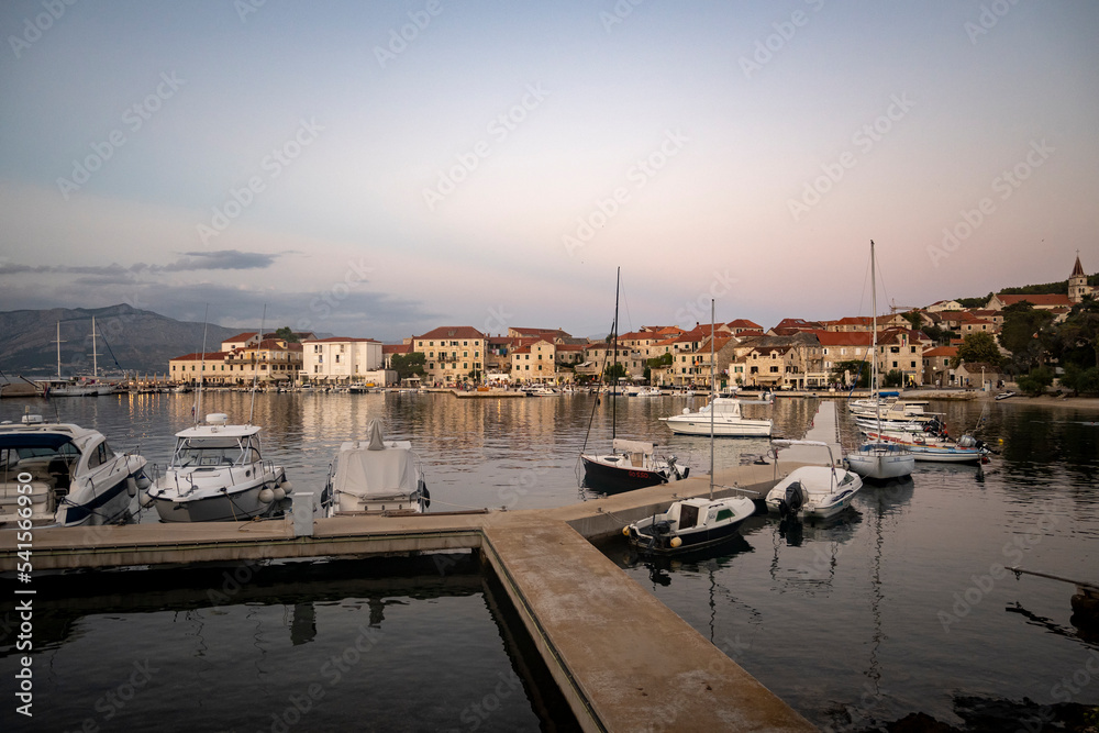 Beautiful sunset over small town of Postira on Brac island, Croatia and port with anchored boats