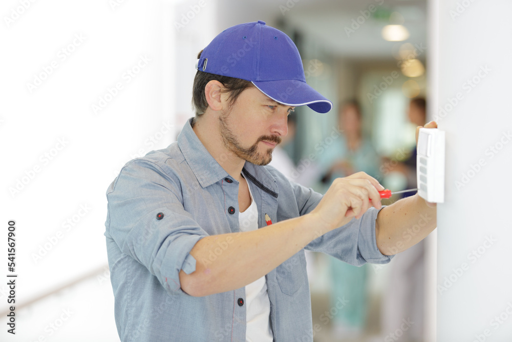 handsome young electrician repairing intercom handsome young electrician repairing intercom