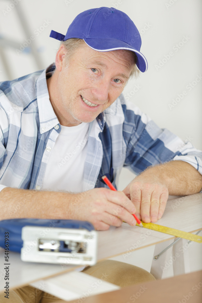 mature male carpenter preparing place to cut wood with jigsaw mature male carpenter preparing place to cut wood with jigsaw