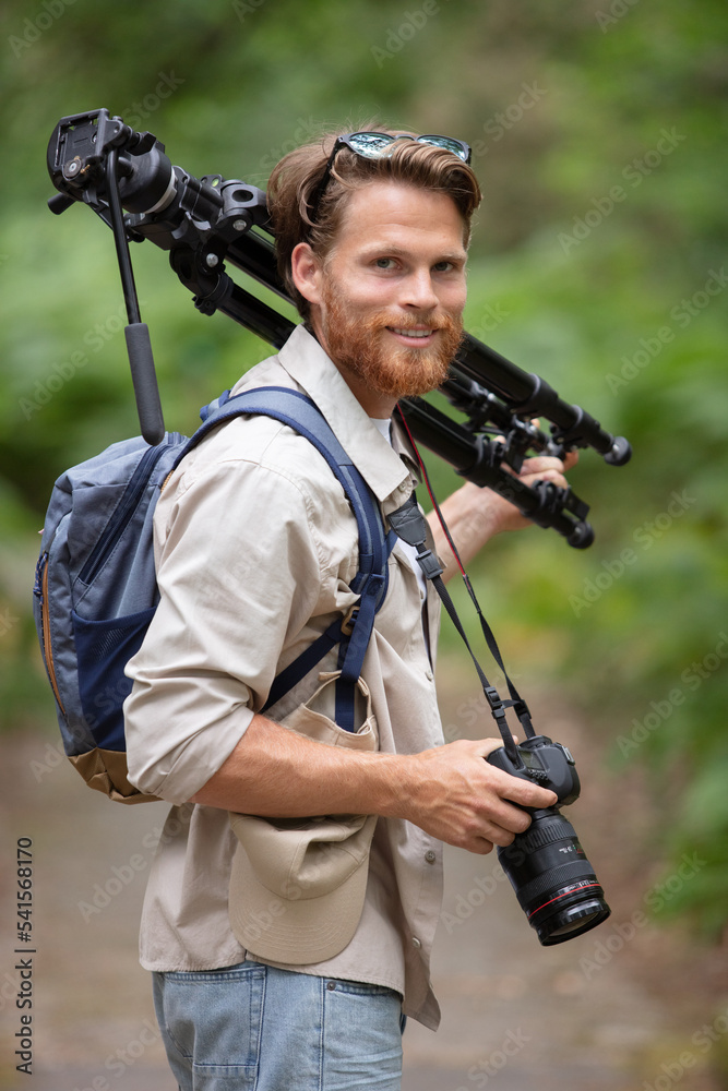 naturalist photographer holding camera and tripod