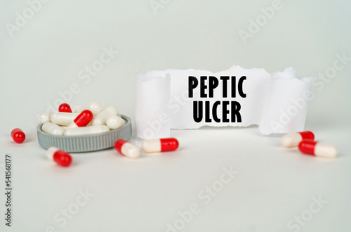 On a gray background, medical capsules and a paper plate with the inscription - Peptic ulcer photo