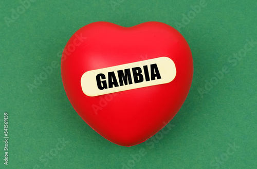 On a green surface lies a red heart with the inscription - Gambia