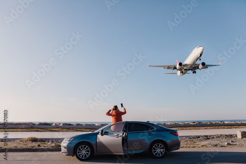 a woman leaned out of the car and filmed a plane landing on her phone