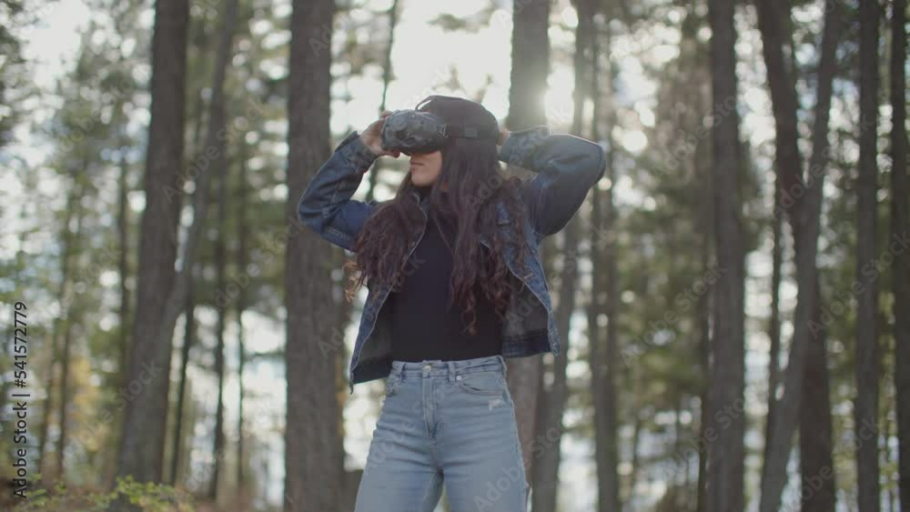 Young woman puts on virtual reality goggles in forest and is amazed Young woman puts on virtual reality goggles in forest and is amazed