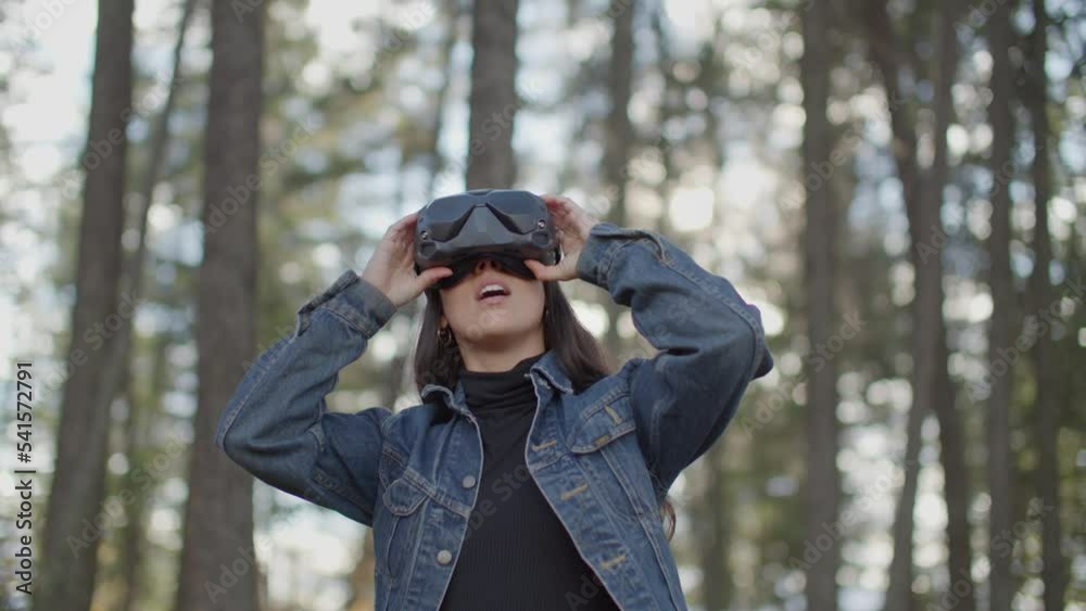 Young woman looking around in virtual reality goggles in the forest Young woman looking around in virtual reality goggles in the forest