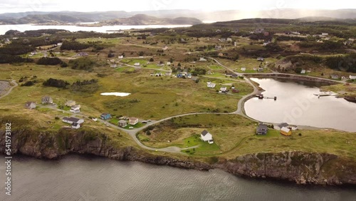 Aerial cinematic view of Newfoundland remote community overlooking rocky cliffs near the Skerwink Hiking Trail and Trinity Bay at Port Rexton Canada.
 photo