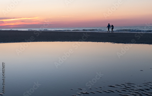 Sunrise silhouette of a couple walking on Coligny beach, Hilton Head, South Carolina. © Chris