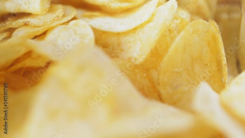A mountain of potato chips lies on the table. Golden chips close-up. Lots of junk food, macro video.