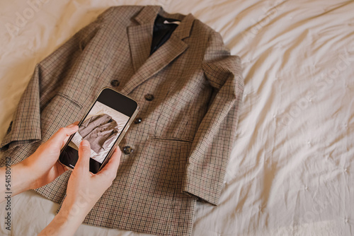 Woman taking picture of her jacket to sell it online photo