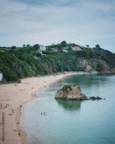 Vertical shot of Goscar rock in north beach Tenby, houses and  green hills in Pembrokeshire Wales photo