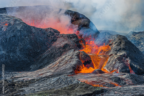 Details of a volcanic crater opening. Lava flows in small amount from crater. active volcano in Iceland of Reykjanes Peninsula. Smoke and steam over the volcanic crater. magma deposit at the crater