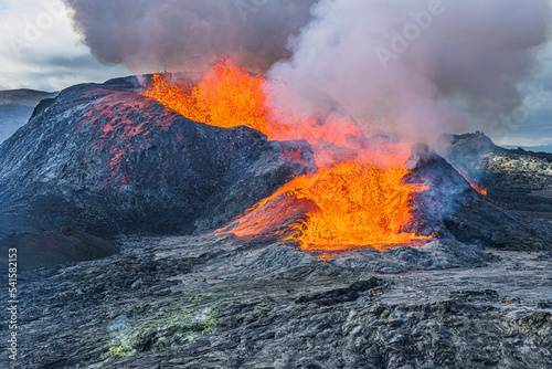 Heavy smoke over an active volcanic crater. Lava flow from an active volcano in Iceland. Landscape on Reykjanes peninsula at day. Hot magma rock around the volcanic crater and dark magma