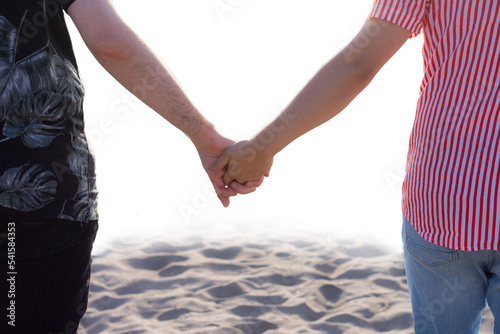 Boyfriends holding hands on the beach, gay couple, pride month