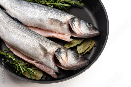 Sea bass fish. Two peeled raw sea bass, spices and rosemary branches in a skillet