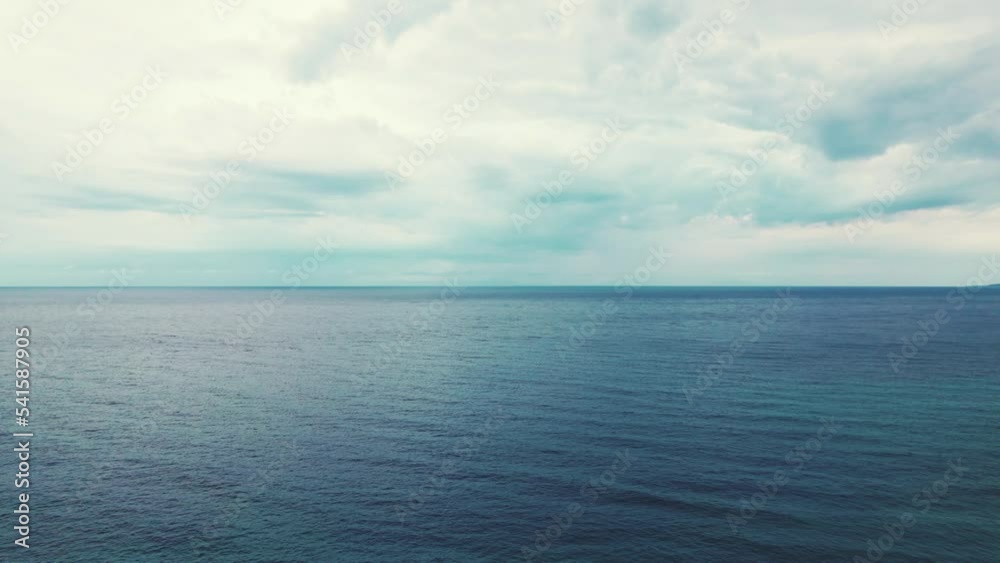 One single person standing high nearby the seashore with hands high in the air. Drone slowly moves towards calm sea. Cloudy sky. Viewing spot in Greece. High quality 4k footage