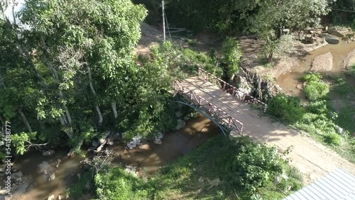 A small wooden old bridge is placed over a small stream in a village in Omkoi district, Chiangmai, Thailand. May 2021. photo