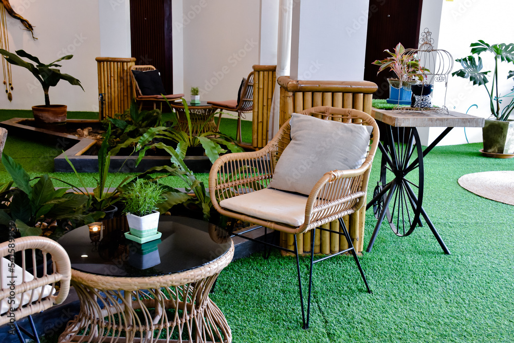 Home living room interior decoration with plastic rattan chairs and pillows and glass round table.