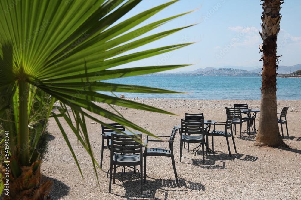 Beautiful view of chairs and tables on sandy beach near sea
