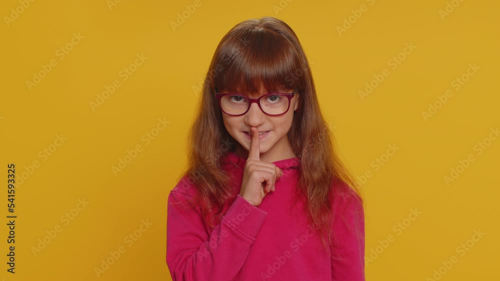 Shh be quiet please. Preteen child girl kid presses index finger to lips makes silence hush gesture sign do not tells gossip secret. Little toddler children isolated alone on studio yellow background Shh be quiet please. Preteen child girl kid presses index finger to lips makes silence hush gesture sign do not tells gossip secret. Little toddler children isolated alone on studio yellow background