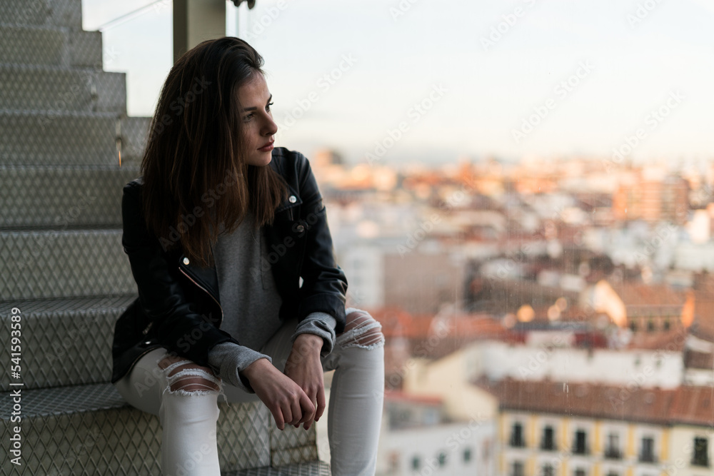Woman sitting on stairs with aerial shot of a big city