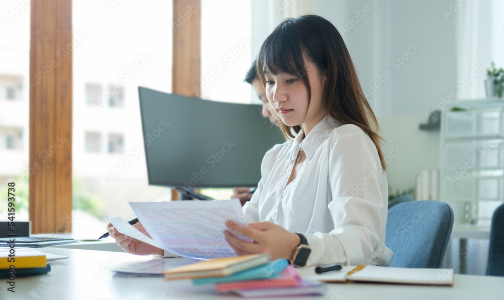 Focused asian female employee working with document and laptop at corporate office... Focused asian female employee working with document and laptop at corporate office...