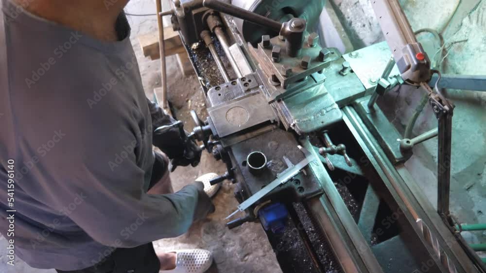 Unrecognizable man working with old workbench in his garage or workshop. Mechanic using lathe for metal processing. View on turning work. Slow motion Close up