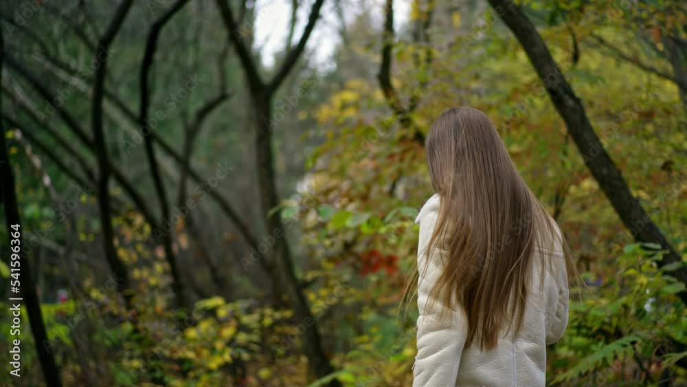 Happy active smiling woman walks in the park with paper cup in her hand. Lady walking looking into camera and waving her hand. Autumn nature backdrop. Happy active smiling woman walks in the park with paper cup in her hand. Lady walking looking into camera and waving her hand. Autumn nature backdrop.