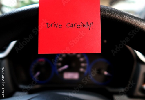 Car console panel with handwritten stick note DRIVE CAREFULLY, concept of car driver self reminder to drive carefully with mindset of safety first, be alert to reduce accidents on the road photo