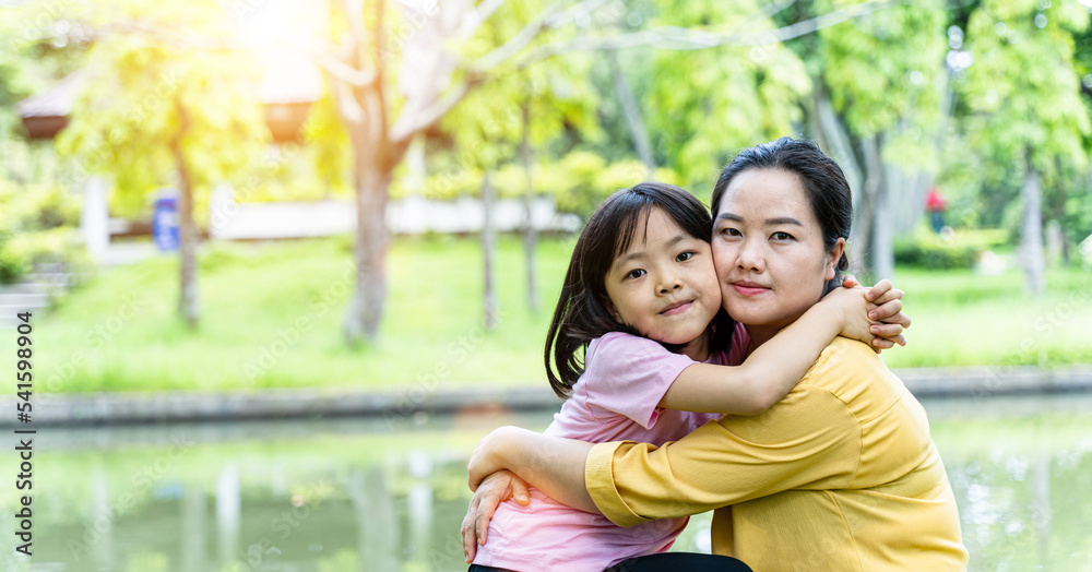Cute young daughter with her mother hugging in love playing together in a park Cute young daughter with her mother hugging in love playing together in a park