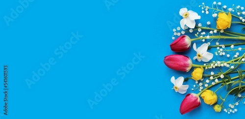 Tulips, daffodils and lilies of the valley on a blue background. Spring flower arrangement. The view from the top. Background for cards, greetings, invitations.